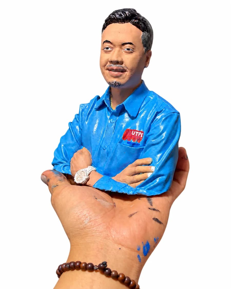 Figure 3D custom pria berbaju biru dari foto, ditampilkan di tangan dengan latar putih